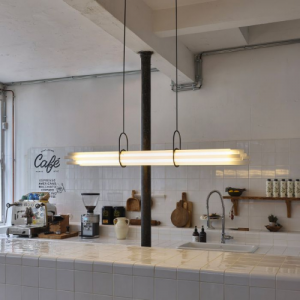 NL12 de chez DCW, suspension lumineuse composée de tubes horizontaux suspendus dans un espace intérieur