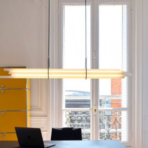 NL12 de chez DCW, suspension lumineuse composée de tubes horizontaux suspendus dans un espace intérieur