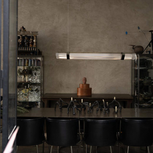 Suspension Seagull de chez DCW composée de tubes lumineux alignés, suspendue au-dessus d’une table