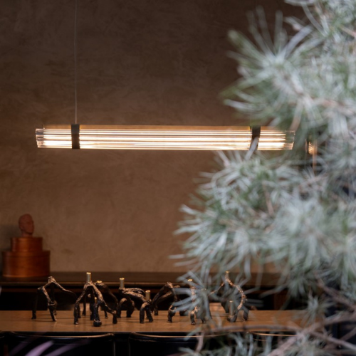 Suspension Seagull de chez DCW composée de tubes lumineux alignés, suspendue au-dessus d’une table