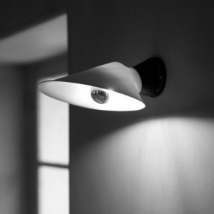 Applique murale Plume de DCW au design fin et courbé diffusant une lumière indirecte douce le long du mur.