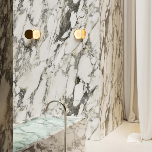 Applique murale Poudrier de DCW, forme circulaire inspirée d’un miroir, diffusant une lumière indirecte douce autour du mur.